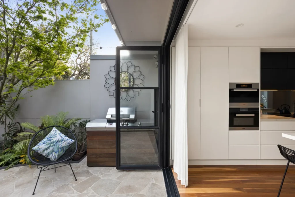 Kitchen opening into an outdoor barbecue area in a heritage renovation by Canstruct Builders.